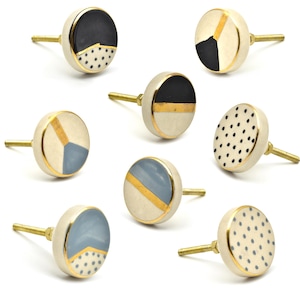 May include: Set of eight ceramic drawer knobs with gold accents. The knobs feature geometric patterns in black, white, and blue.