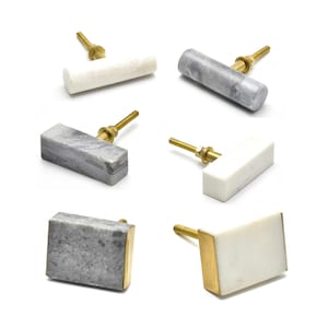 Könnte beinhalten: Sechs verschiedene Marmor-Schubladengriffe mit Messingakzenten. Die Griffe sind in verschiedenen Formen und Größen, darunter rechteckig, quadratisch und rund.