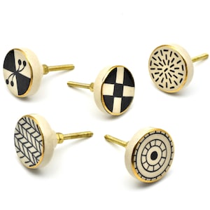 Pode incluir: Conjunto de seis botões de gaveta de cerâmica com padrões geométricos em preto e branco e acabamento dourado. Cada botão tem um design diferente.