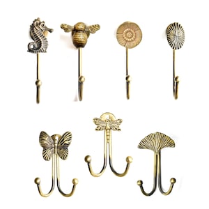 Può includere: Una collezione di ganci decorativi in metallo color bronzo, con vari disegni tra cui un cavalluccio marino, un'ape e un fiore. Questi ganci sono adatti per appendere oggetti. I ganci sono montati su uno sfondo bianco. Ogni gancio è in metallo.
