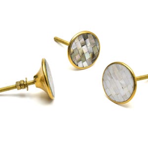 Peut inclure: Trois boutons de porte en or avec un incrustation ronde en nacre blanche. Les boutons ont une finition en laiton et un design simple et élégant.