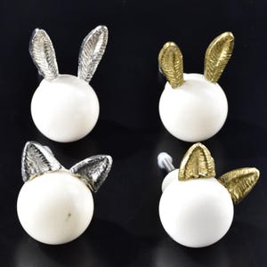 May include: Four white ceramic bunny door knobs with gold and silver bunny ears.