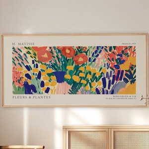 May include: A rectangular wall art print in a light wood frame featuring a colourful abstract floral painting by H. Matisse titled FLEURS & PLANTES. The artwork displays vibrant red, yellow, and blue brushstrokes on a cream background with text.