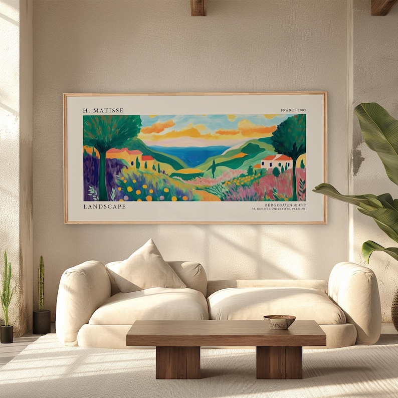 May include: A framed landscape art print by H. Matisse. The artwork depicts a colorful scene with rolling hills, trees, houses, and a body of water. The print has the words "LANDSCAPE" and "FRANCE 1965" printed on it.