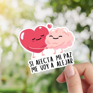 May include: A sticker featuring a red heart and a pink brain, both with smiling faces, embracing. The sticker has the Spanish text "SI AFECTA MI PAZ ME VOY A ALEJAR" in white letters.