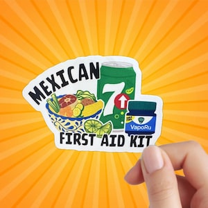 May include: A white sticker with the text "Mexican First Aid Kit" in black. The sticker features a bowl of Mexican food, a can of 7 Up, and a small jar of VapoRub.