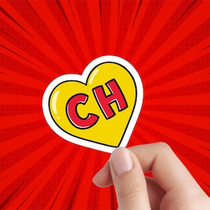 May include: A yellow heart-shaped sticker with a white outline and the letters "CH" in red inside. The sticker is being held by a hand against a red and white background.