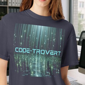 May include: A dark gray t-shirt featuring a graphic print of vertical light blue digital code streams and binary numbers. The text CODE-TROVERT is printed in a light blue sans-serif font across the center of the digital matrix design.
