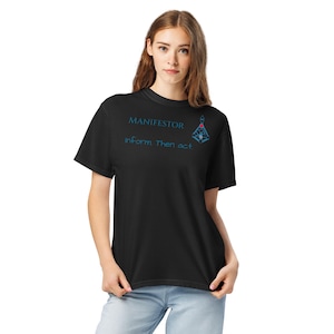 May include: Black t-shirt with the word "MANIFESTOR" and the phrase "inform Then act" in blue. A geometric design is also in blue. The shirt is being worn by a person.