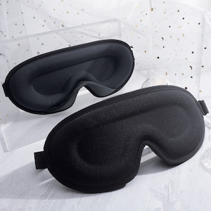 May include: Two black sleep masks with contoured eye cups. The masks are made of a soft, plush material and have adjustable straps. Designed to block out light for improved sleep, they are ideal for travel.