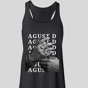 Puede incluir: Camiseta sin mangas negra con el texto blanco "AGUST D". La imagen muestra manos adornadas con m&uacute;ltiples anillos y una pulsera. La camiseta sin mangas tiene un dise&ntilde;o de espalda deportiva.