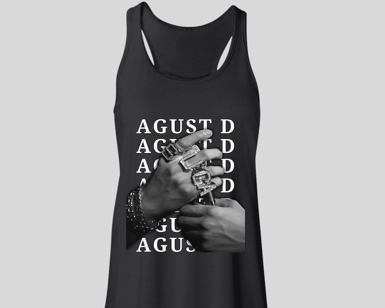 Puede incluir: Camiseta sin mangas negra con el texto blanco "AGUST D". La imagen muestra manos adornadas con m&uacute;ltiples anillos y una pulsera. La camiseta sin mangas tiene un dise&ntilde;o de espalda deportiva.