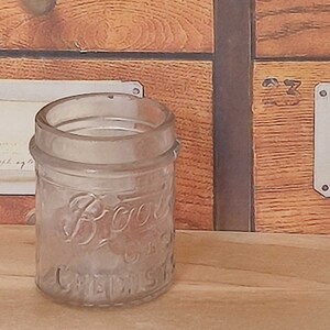 May include: A clear glass jar with a textured surface. The jar has the words "Boots Chemist" printed on the front.