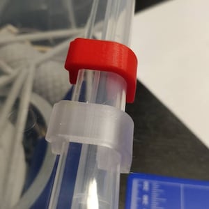 May include: A clear plastic storage container with a red plastic latch. The latch is attached to the side of the container and is used to secure the lid.