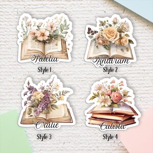 May include: Four different styles of book stickers with floral designs and names. The stickers feature a book with flowers on top, with the names Fidelia, Antaram, Oralie, and Calista. Each sticker has a style number below the name.