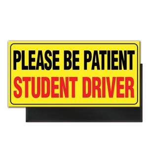 May include: A rectangular yellow sign with black text that reads "PLEASE BE PATIENT" above "STUDENT DRIVER" in red. The sign has a black border and a black shadow.