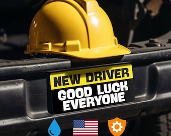 May include: A yellow hard hat sits above a rectangular bumper sticker with a yellow top section reading NEW DRIVER and a black bottom section reading GOOD LUCK EVERYONE. Below are icons for waterproof, Made in USA, and durable features.