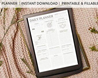 Peut inclure: Un planificateur quotidien noir et blanc sur une tablette avec des sections pour l'humeur, les objectifs du jour, le rendez-vous du jour, l'exercice, l'apport en eau, le suivi des repas, à appeler ou à envoyer un courriel, le suivi de l'argent, les notes et pour demain. Le planificateur est sur une surface en tricot rose.