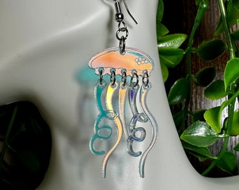 May include: A pair of iridescent jellyfish earrings with a silver hook. The jellyfish are translucent and have a light orange body with blue tentacles.