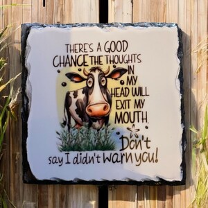 May include: A rectangular decorative slate sign with a white background and a black border. The sign features a cartoon cow and the text "THERE'S A GOOD CHANCE THE THOUGHTS IN MY HEAD WILL EXIT MY MOUTH. Don't say I didn't warn you!"