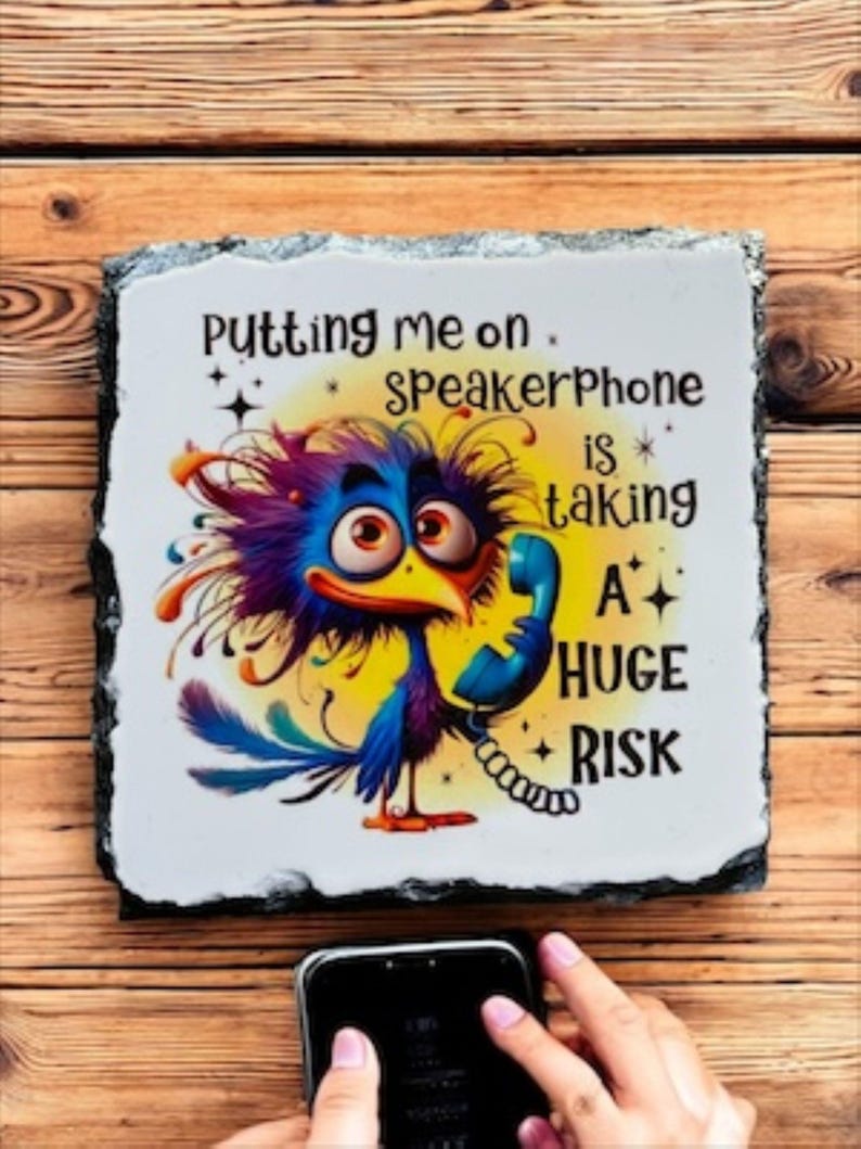 May include: A decorative slate sign with a cartoon bird holding a phone, with the text "Putting me on speakerphone is taking a HUGE RISK." The sign is on a wooden surface.