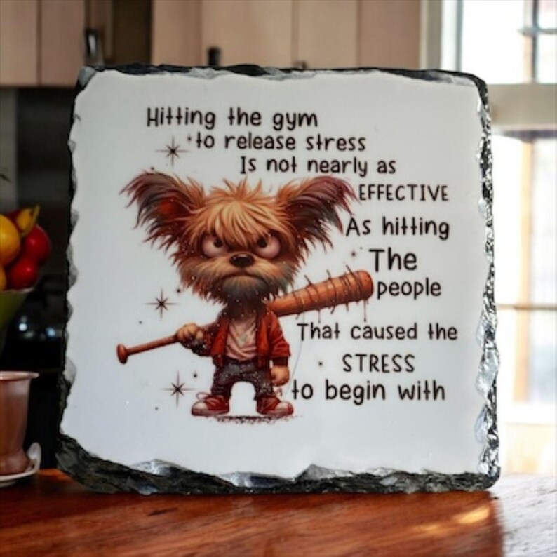 May include: A decorative stone plaque with a humorous illustration of a cartoon dog holding a baseball bat. The text reads "Hitting the gym to release stress is not nearly as EFFECTIVE as hitting the people that caused the STRESS to begin with."