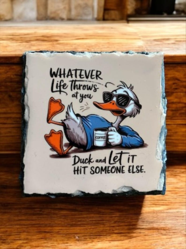 May include: Square stone coaster with a cartoon duck wearing sunglasses and holding a coffee cup. The text reads "Whatever Life Throws at You, Duck and Let It Hit Someone Else."