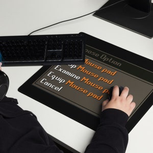 Może przedstawiać: Czarna podkładka pod mysz z menu na ekranie, kt&oacute;re wyświetla "Mouse Option" i zawiera następujące opcje: "Mouse pad", "Examine Mouse pad", "Equip Mouse pad" i "Cancel".