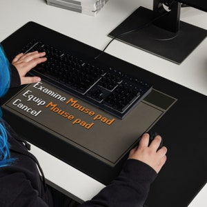 Może przedstawiać: Czarna podkładka pod mysz z szarym paskiem menu, na kt&oacute;rym widnieje napis "Examine Mouse pad", "Equip Mouse pad" i "Cancel". Osoba używa klawiatury i myszy na podkładce.