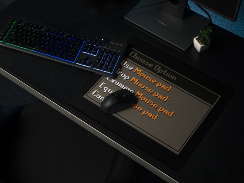 Może przedstawiać: Czarna mysz komputerowa leży na ciemnoszarej podkładce pod mysz z tekstem "Wybierz opcję" i listą opcji: "Użyj podkładki pod mysz", "Upuść podkładkę pod mysz", "Zbadaj podkładkę pod mysz", "Wyposaż podkładkę pod mysz", "Może być podkładka pod mysz".