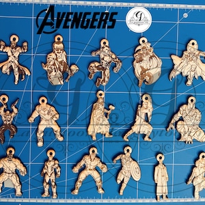 Op de afbeelding: Een set van 16 houten ornamenten met personages uit de Avengers-filmfranchise. De ornamenten zijn lasergesneden en gegraveerd met gedetailleerde afbeeldingen van de personages, waaronder Iron Man, Captain America, Thor, Hulk, Black Widow, Hawkeye, en meer. De ornamenten zijn allemaal ongeveer 5 cm groot en hebben een gat aan de bovenkant om ze op te hangen.