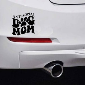 May include: A white car with a black decal that says "Anti Social Dog Mom" with a paw print in the middle of the word "Dog".