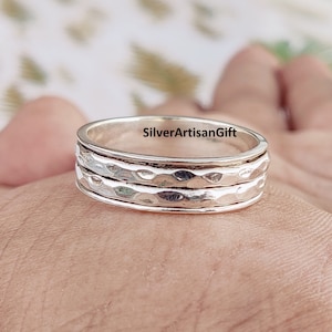 May include: A silver spinning ring with a hammered texture. The ring is made of three bands that spin freely around each other.