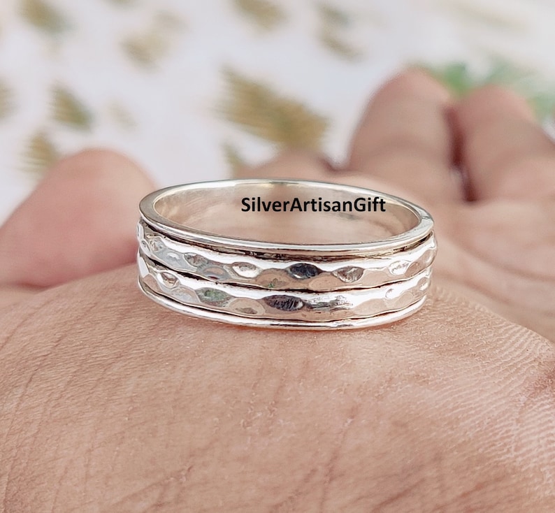 May include: A silver spinning ring with a hammered texture. The ring is made of three bands that spin freely around each other.