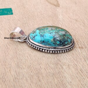 May include: A turquoise gemstone pendant with a silver setting. The pendant has a rope-like border and a silver bail.
