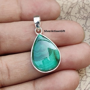 May include: A teardrop-shaped pendant featuring a polished green malachite stone set in a silver-colored metal frame. The malachite displays natural swirling patterns. The pendant has a small loop at the top for a chain.