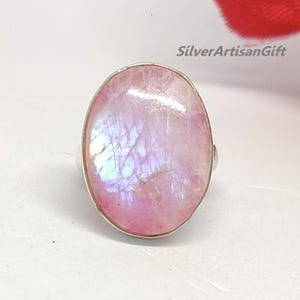 May include: A silver ring with a large oval pink moonstone. The stone has a iridescent sheen.