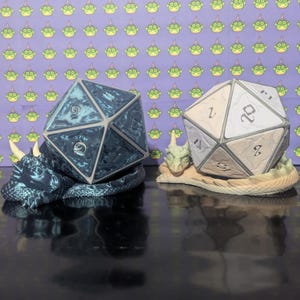 May include: Two dice in the shape of a dragon, one is blue and the other is white. The dice are sitting on a dragon-shaped stand.
