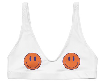 May include: White sports bra with two orange smiley faces printed on the front.