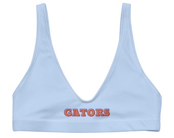 May include: Light blue bikini top with white stitching and the word "GATORS" in orange and blue lettering.