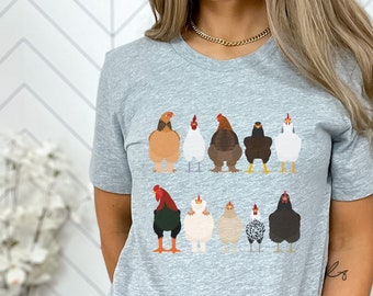 Puede incluir: Camiseta gris con un gráfico de una línea de pollos mirando al espectador. Los pollos son de varios colores y razas.