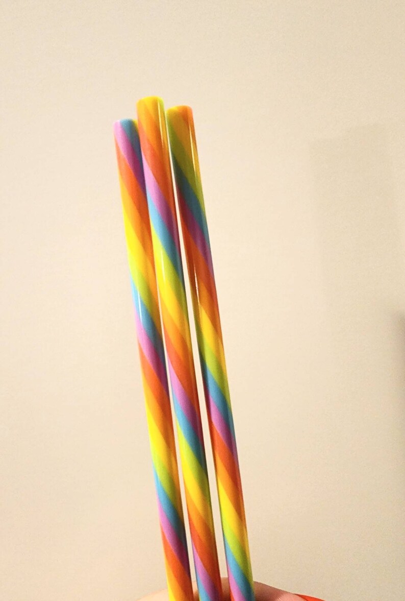 Pu&ograve; includere: Tre cannucce da bere a righe arcobaleno. Le cannucce sono gialle, arancioni, rosse, viola, blu e verdi.