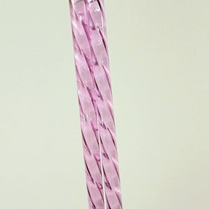 Pu&ograve; includere: Due cannucce da bere in vetro rosa con un design intrecciato.