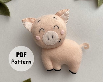 May include: A handmade felt pig in a light pink color with a smiling face, small black feet, and a curled tail. The pig has a white snout and ears with pink accents. The text "PDF Pattern" is in a white circle.