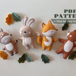 May include: A collection of handmade felt woodland animal toys, including a deer, rabbit, fox, and bear, with felt leaf accents. The toys are in shades of brown, tan, and orange, with white bellies and smiling faces. The text "PDF PATTERN + Step-by-step instruction" is also visible.