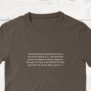 May include: A brown t-shirt with white text that reads: "Defined by taking the fixed numerical value of the cesium frequency ΔνCs, the unperturbed ground-state hyperfine transition frequency of the cesium-133 atom, to be 9,192,631,770 when expressed in the unit Hz, which is equal to s-1."