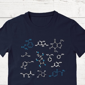 May include: A navy blue t-shirt with a variety of chemical structures printed on it in blue and white. The structures are of different sizes and shapes, and some have labels with chemical symbols and names.