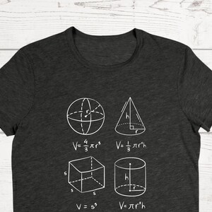 May include: A dark gray t-shirt with a white graphic of geometric shapes and formulas for calculating volume. The shapes include a sphere, cone, cube, and cylinder.