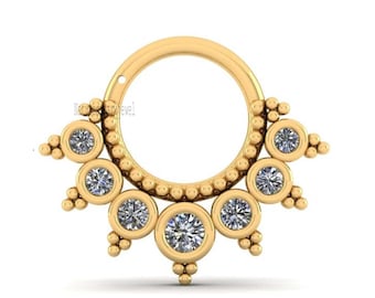 May include: Gold septum ring with a circular design featuring multiple small round clear gemstones. The ring is adorned with small beads around the outer edge.