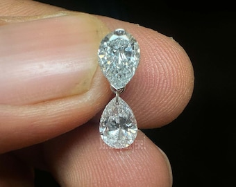 May include: A pair of pear-shaped diamond earrings with a silver setting. The earrings are dangling and have a teardrop shape.